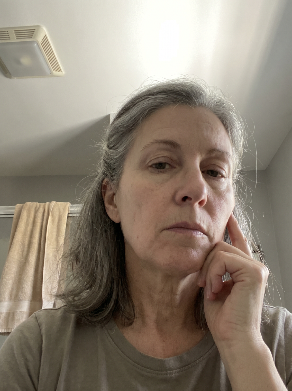 Woman studying her reflection in the bathroom mirror, morning light